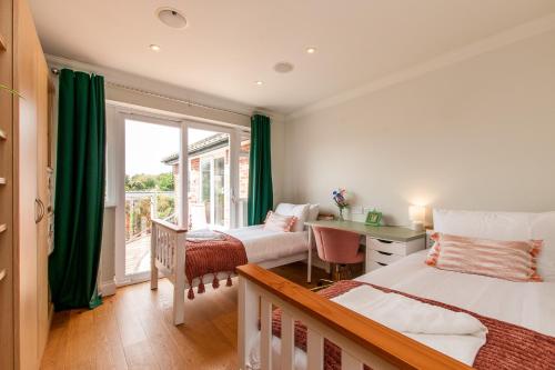 a bedroom with two beds and a desk and a window at Botany Bay Beach House - Stunning Sea Views in Kingsgate