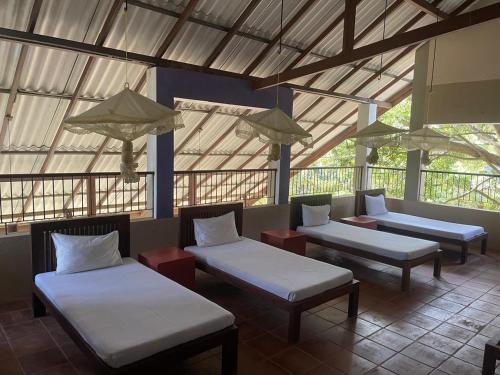 a room with three beds and tables in a building at Wildlight Yala in Yala