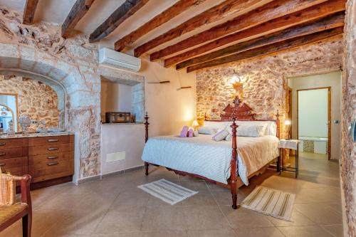 a bedroom with a bed and a stone wall at Na Corma Nova by dracmallorca in Calonge