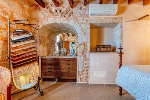 a bedroom with a stone wall and a bed and a mirror at Na Corma Nova by dracmallorca in Calonge