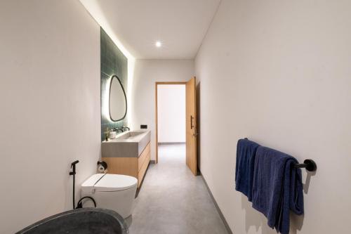a bathroom with a sink and a toilet and a mirror at Villa Chilla - New Modern Loft in Prime Uluwatu in Uluwatu