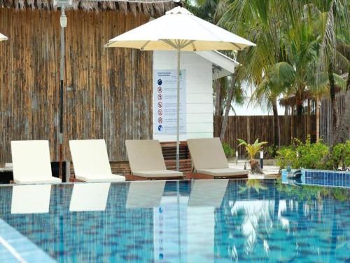 a swimming pool with two chairs and an umbrella at Nov Koh Kong Resort in Phumĭ Srê Thmei