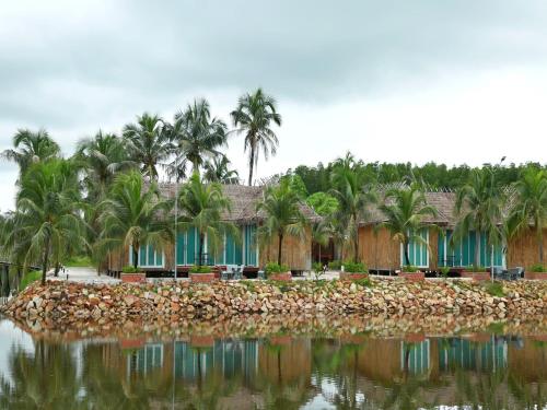 a resort with palm trees and a body of water at Nov Koh Kong Resort in Phumĭ Srê Thmei