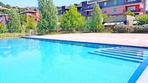 une grande piscine avec de l'eau bleue dans un immeuble dans l'établissement Appartement Rive Nature coté parc et rivière, à Saint-Raphaël