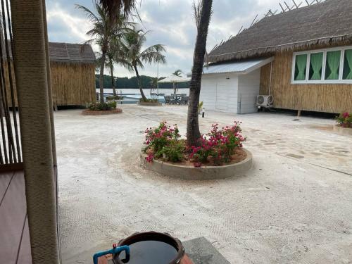 a house with a tree and flowers in a courtyard at Nov Koh Kong Resort in Phumĭ Srê Thmei