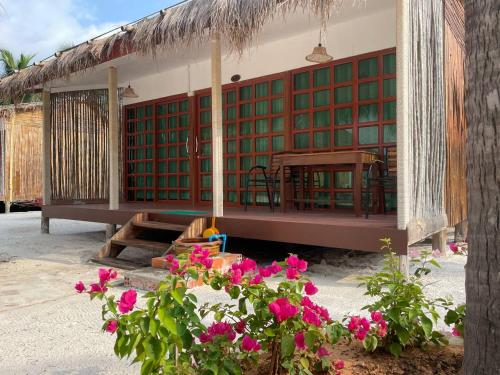 a building with green and red shutters and pink flowers at Nov Koh Kong Resort in Phumĭ Srê Thmei