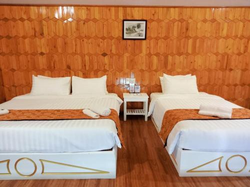 two beds in a room with wooden walls at Nov Koh Kong Resort in Phumĭ Srê Thmei