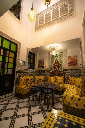 a living room with yellow couches and a table at Riad Dar Jnan Sbil in Fès