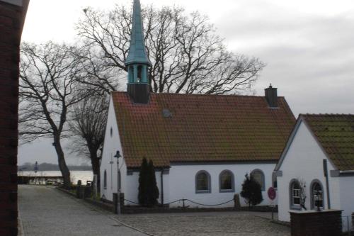 a small white church with a steeple on top of it at Bruhn's Ferienwohnung Seehund in Maasholm
