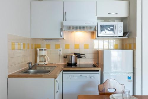a small kitchen with a sink and a refrigerator at Résidence Odalys Soleil d'Aure in Saint-Lary-Soulan