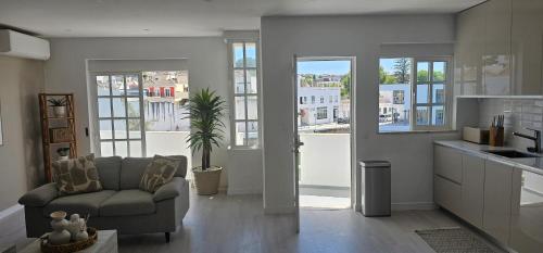 a living room with a couch and a kitchen with windows at River View Tavira - New Listing, Newly Renovated in Tavira
