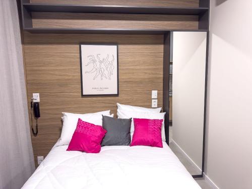 a bedroom with a large bed with pink and grey pillows at ST Studios Vila Mariana by Housi in Sao Paulo