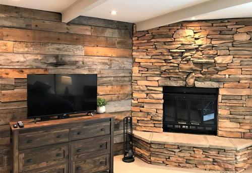 a stone fireplace in a living room with a television at Beautiful suite with superb mountain view. in Mont-Tremblant
