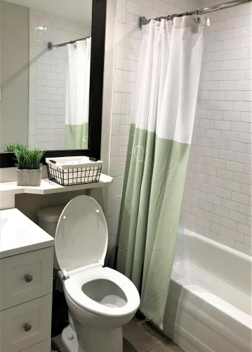 a bathroom with a toilet and a shower curtain at Beautiful suite with superb mountain view. in Mont-Tremblant