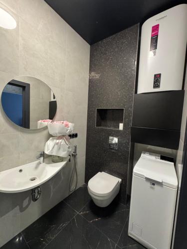 a bathroom with a sink and a toilet and a mirror at Arcadia Apartments in Odesa