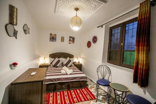 a bedroom with a bed and two chairs and a window at Riad Dar Jnan Sbil in Fès