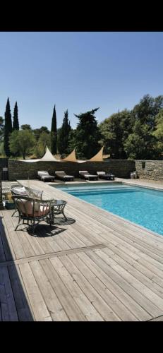 une terrasse en bois avec une table à côté d'une piscine dans l'établissement Les Pins, à Laure-Minervois