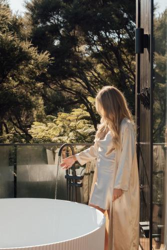a woman is standing next to a bath tub at Wahapu Lodge - Luxury sea views in Russell