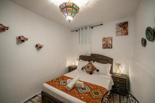 a bedroom with a bed and a chandelier at Riad Dar Jnan Sbil in Fès