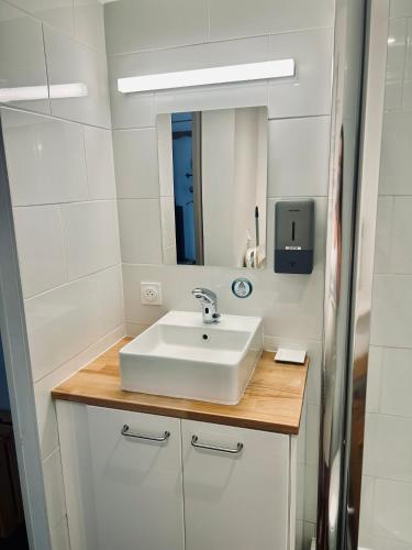 une salle de bain avec un lavabo blanc et un miroir dans l'établissement Studio de charme proche Nantes & aéroport au calme, à Rezé