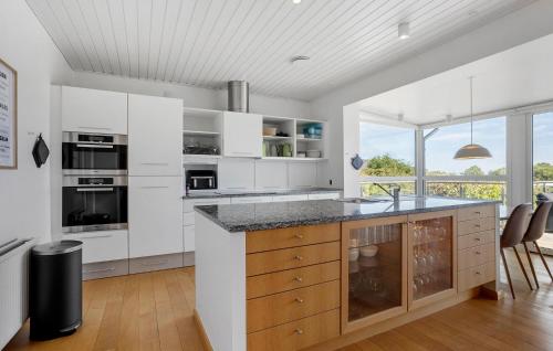 a kitchen with white cabinets and a large window at Five Bedroom Beautiful Home In Sindal in Sindal