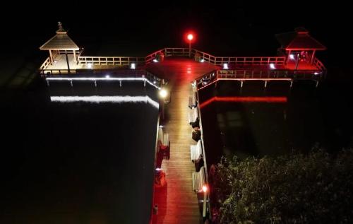 a bridge with red lights on the water at night at Anders Home 1 Szczytno in Szczytno