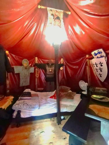 une chambre avec une tente rouge avec un lit et une lampe dans l'établissement Le Camp du Chevalier, à Valençay