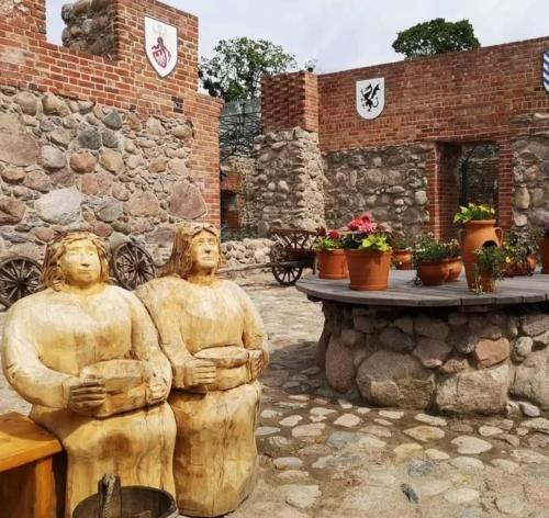 two statues of people sitting on a bench in front of a building at Anders Home 1 Szczytno in Szczytno