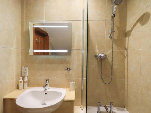 a bathroom with a sink and a shower with a mirror at Lakeside Cottage in Windermere