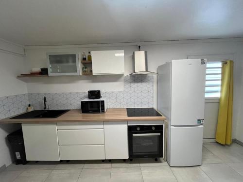 a kitchen with white cabinets and a refrigerator at Duplex La Petite Perle avec son jardin privé in Le Lamentin
