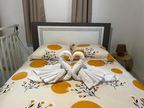 two swan towels are laying on a bed at Duplex La Petite Perle avec son jardin privé in Le Lamentin