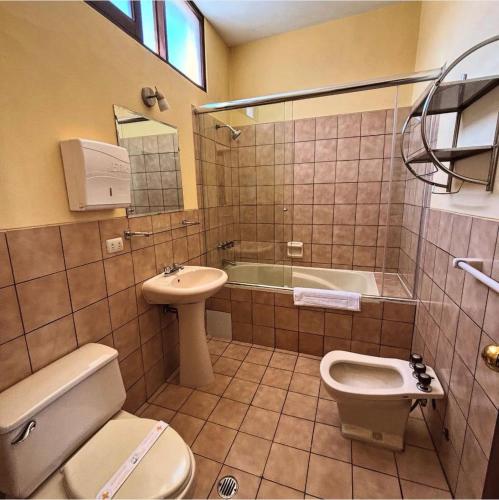 a bathroom with a toilet and a sink and a tub at Hotel Meliana in Arequipa