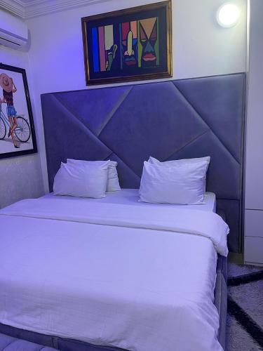 a bedroom with a large white bed with a blue headboard at Swazshortlet in Gwarinpa