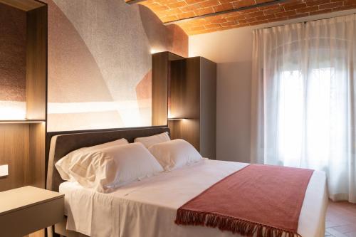 a bedroom with a bed with white sheets and a window at Borgo Bucciano in San Miniato