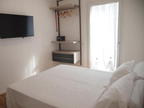 a white bedroom with a bed and a tv at Hotel Vienna in Pesaro