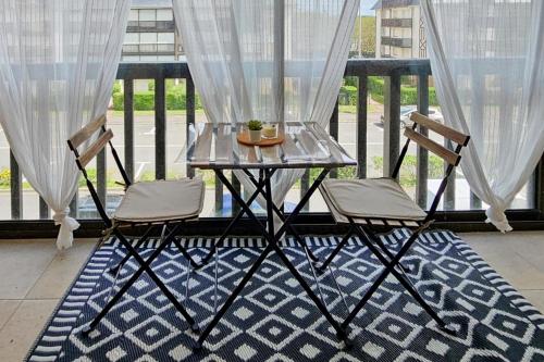 d'une table en verre et de deux chaises sur un balcon. dans l'établissement Cozy and bright renovated apartment, à Villers-sur-Mer
