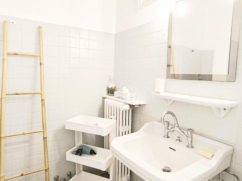 une salle de bain blanche avec un lavabo et un miroir dans l'établissement Studio au calme 100 mètres de la croisette, à Cannes