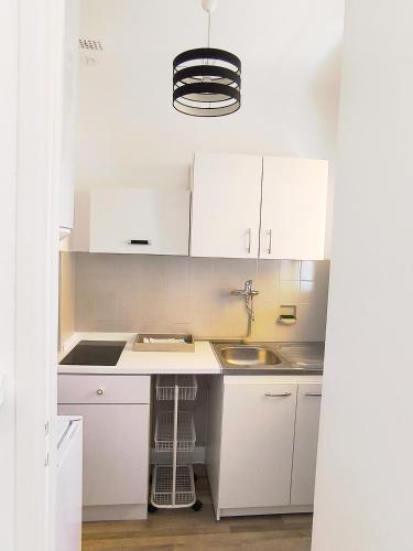 une cuisine blanche avec des armoires blanches et un évier dans l'établissement Studio au calme 100 mètres de la croisette, à Cannes