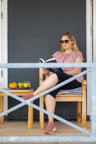 a woman sitting on a bench reading a book at Hørby Færgekro in Holbæk