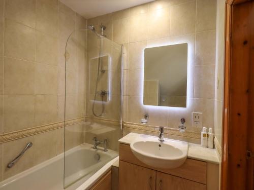 a bathroom with a sink and a tub and a mirror at Waterhead Cottage in Windermere