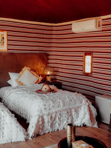 a bedroom with a bed with a white comforter at Agafay Yes We Camps & Spa in El Karia