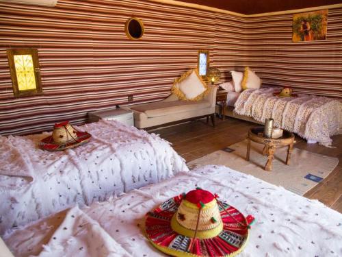 a room with two beds and a living room with at Agafay Yes We Camps & Spa in El Karia