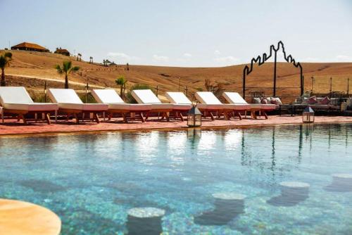 a row of lounge chairs next to a swimming pool at Agafay Yes We Camps & Spa in El Karia