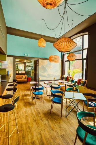 a restaurant with tables and chairs and windows at Hotelo Lyon Ainay in Lyon