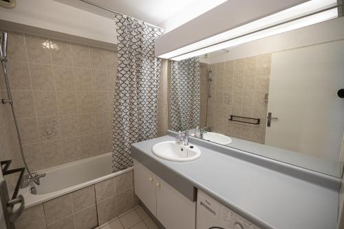 une salle de bain avec un lavabo, un miroir et une baignoire dans l'établissement Le Grand Bleu, à Wimereux