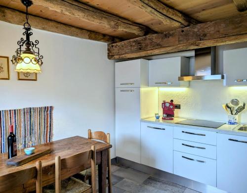 a kitchen with white cabinets and a wooden table at Borgo Selvapiana in Morbegno