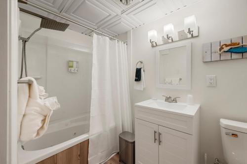 a white bathroom with a shower and a sink at The Beachside in Sylvan Beach