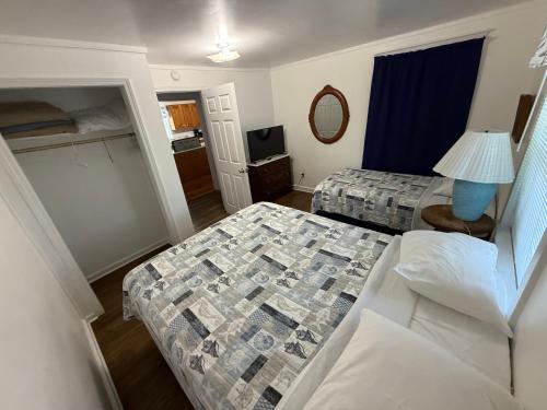 a small bedroom with two beds and a mirror at Outer Banks Motel - Village Accommodations in Buxton