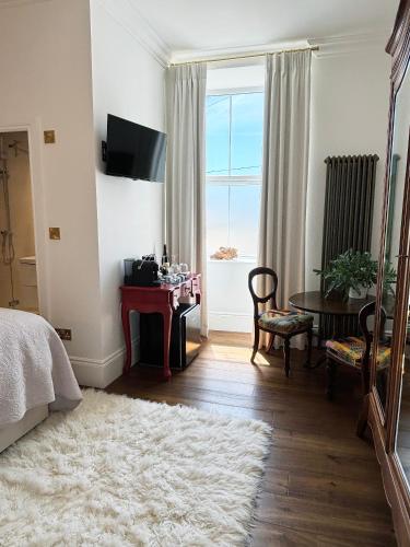 a bedroom with a bed and a table and a window at Headland View Boutique B&B in Torquay