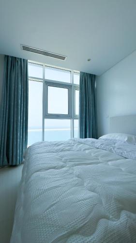 a white bed in a room with windows at الموج in Ḩayl Āl ‘Umayr